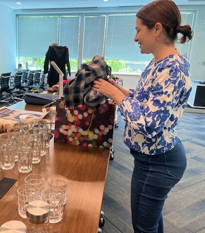 Two people looking through items on tables at FMP's Secondhand Market. One person is holding up an item of clothing.