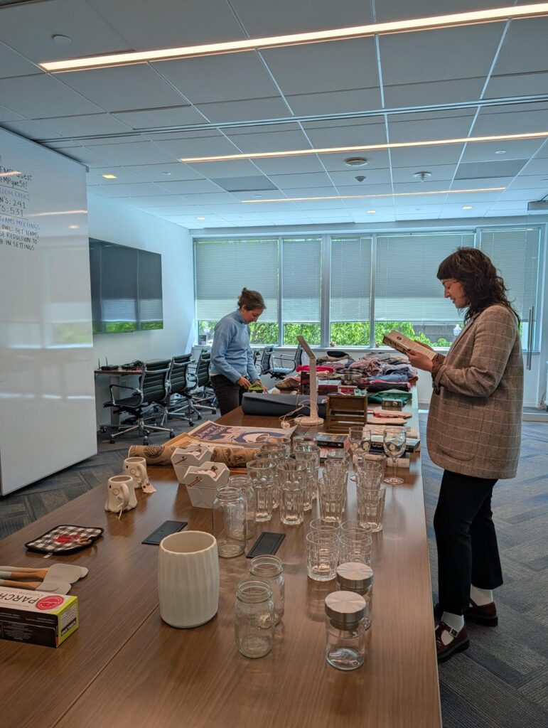 Two people looking through items on tables at FMP's Secondhand Market. One person is holding open a book.