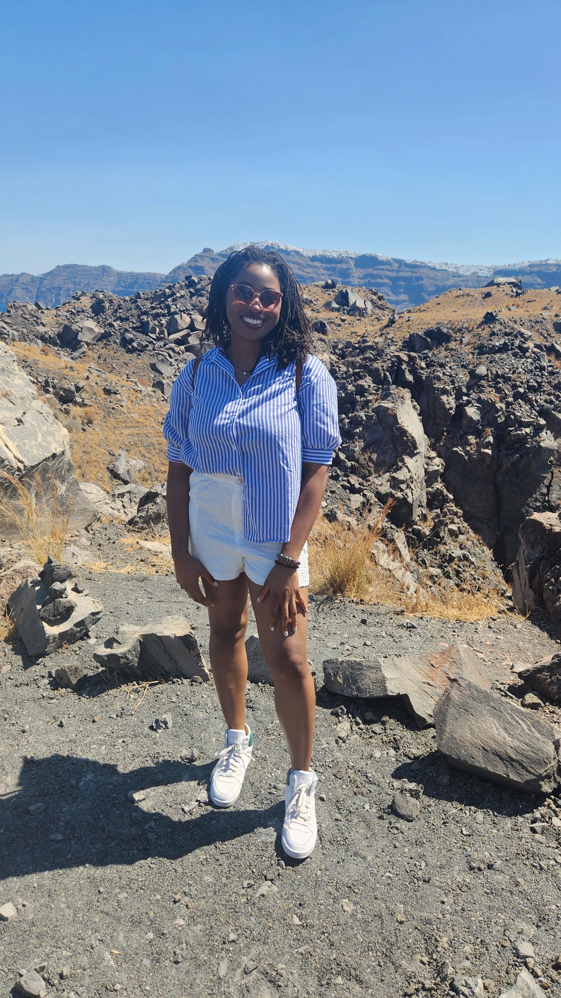 A woman standing in rocky terrain among mountains. 