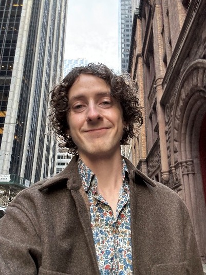 A man with the sky and tall buildings behind him.